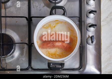 Salsicce di ebollizione sulla stufa Foto Stock