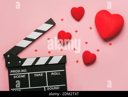 Buon giorno di San Valentino.clapperboard con cuori rossi su uno sfondo rosa.Romantico concetto di film Foto Stock