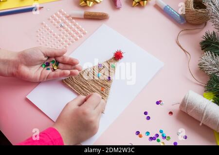 Il bambino crea una tessera di Capodanno per le vacanze invernali. Artigianato fai da te e artigianato per il concetto di Natale fai da te Foto Stock