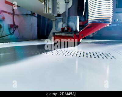 Vista generale di una macchina CNC che taglia un pannello di polietilene in uno stabilimento di produzione di materie plastiche. Foto Stock