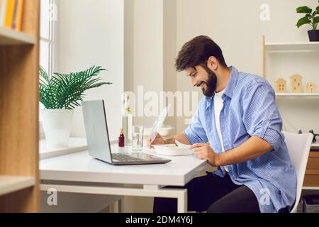 Felice giovane uomo gustando fresco e sano pasto da asporto durante il pranzo pausa al lavoro Foto Stock