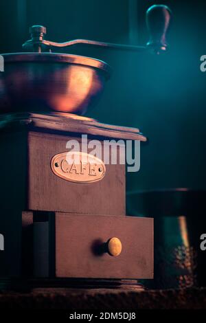 Macinacaffè d'epoca, in tonalità scure su rustico sfondo in legno. Vecchia attrezzatura per la preparazione del caffè. Messa a fuoco selettiva. Profondità di campo poco profonda. Foto Stock