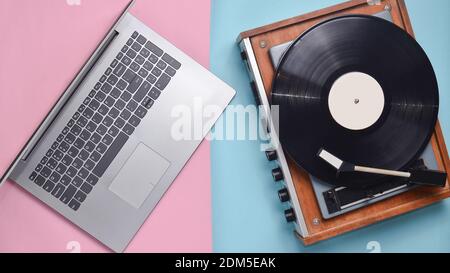Computer portatile, lettore di vinile su sfondo colorato color pastello. Tecnologia moderna e obsoleta, vista dall'alto Foto Stock