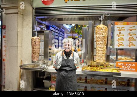 Istanbul, Turchia - 14 febbraio 2020: Uno chef sorridente e venditore di fast food doner kebabs si trova di fronte al suo negozio in via Istiklal, Beyoglu Foto Stock