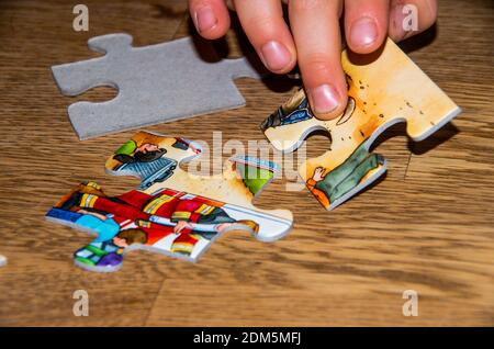 La mano dei bambini prende il pezzo di puzzle sul tavolo di legno con il puzzle pezzi Foto Stock