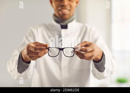 L'ottico sorridente tiene nuovi occhiali di buona qualità e vi suggerisce provali Foto Stock