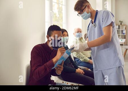 L'uomo afroamericano firma le carte che il medico gli dà prima di ottenere vaccino in ospedale Foto Stock