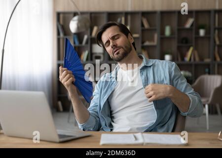 L'uomo stanco soffre di caldo clima ondulato con la mano ventilatore Foto Stock