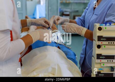 Medici e infermieri utilizzano strumenti per le procedure anestesiologiche sul paziente nella macchina per anestesia all'interno della sala operatoria. Foto Stock