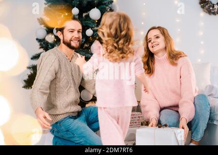 La famiglia felice dà i regali di Natale della loro figlia. La bambina gioisce giftbox Foto Stock