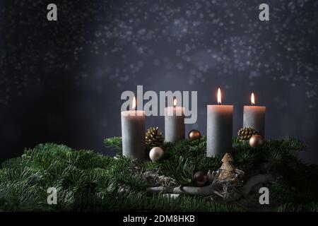 Quarto avvento con quattro candele brucianti su rami di abete con decorazione di Natale contro uno sfondo grigio scuro, spazio di copia, fuoco selezionato, stretto d Foto Stock