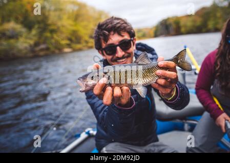 L'uomo tiene fuori il pesce di chub davanti a lui dentro una barca Foto Stock