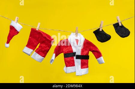 babbo natale vestito appeso fuori per asciugare su sfondo giallo Foto Stock