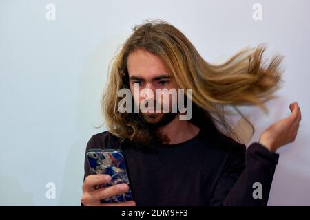Un primo piano di un giovane uomo attraente con un barba che gli piega i capelli Foto Stock
