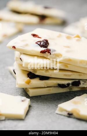 Pila di pezzi di corteccia di cioccolato bianco con mirtillo rosso e macadamia dadi Foto Stock