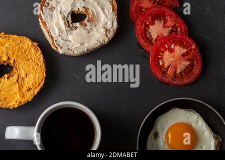 Una colazione nutriente bilanciata o uno spuntino per una persona con un bagel di sesamo tostati e tagliati a metà con formaggio spalmato su fette di t Foto Stock