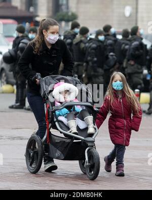 Una donna che indossa una maschera facciale come misura preventiva contro la diffusione del coronavirus COVID-19 cammina con i suoi bambini nel centro di Kiev. Foto Stock