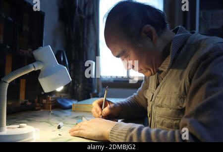 (201216) -- JINAN, 16 dicembre 2020 (Xinhua) -- Wang Tianming carve una scultura in miniatura a Jinan, nella provincia di Shandong, nella Cina orientale, il 16 dicembre 2020. Il micro-scultore Wang Tianming, 71 anni, è un maestro di arte e artigianato di livello provinciale conosciuto per le sue sculture in miniatura. Wang non solo può carve figure microscopiche su giada, bollitori del tè e grani di riso, ma anche su un singolo filo di capelli umani. L'artista ha lavorato meticolosamente in modo dettagliato figure per 35 anni. La micro-scultura, negli occhi di Wang, è un'arte artigianale di sentire. Tuttavia la sensazione può essere acquisita solo lungo il giorno dopo giorno pract Foto Stock
