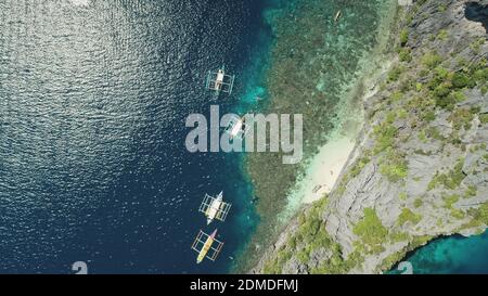 In cima alle barche tradizionali con vista aerea della costa rocciosa dell'oceano. Maestosa condimenti con vasi al sole che brillano sulla superficie dell'acqua. Vacanza estiva crociera a El Nido Island, Filippine, Asia Foto Stock