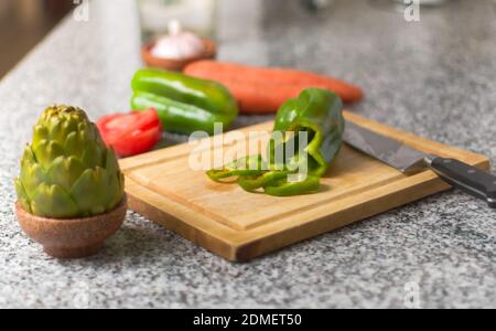 Peperone su un tagliere, e ingredienti freschi su un piano di cucina. Foto Stock