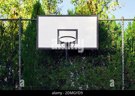 Cerchio da basket all'aperto in un campo montato su una recinzione filo su sfondo blu Foto Stock