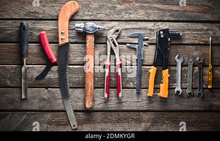 Utensile di lavoro su un tavolo di legno. Sega, martello, cacciaviti, pinze, dime, coltello, vista dall'alto Foto Stock