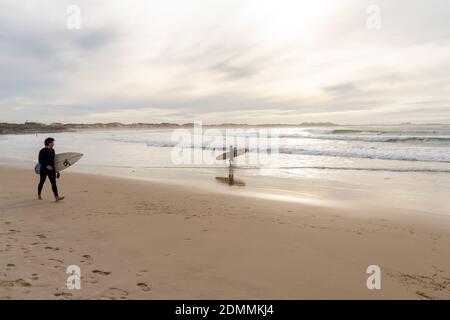 Baleal, Beira Litoral - Portogallo - 13 Dicembre 2020: Surfista che cammina sulla spiaggia di Baleal e guarda altri surfisti che catturano le onde Foto Stock