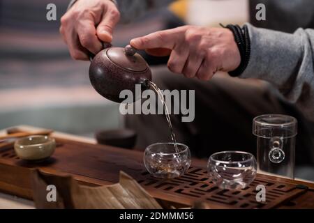 Un uomo tratta un ospite di autentico tè vietnamita maturo su una speciale tavola di gongfu fatta di bambù. Tradizioni del tè orientale bere Foto Stock