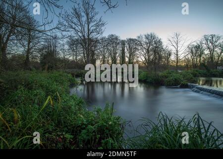 Merton, London, UK. 17 December 2020. Clear sky and mild temperatures at dawn in south west London, only 8 days before Christmas Day, with the River Wandle crossing a weir in Morden Hall Park. Credit: Malcolm Park/Alamy Live News. Stock Photo