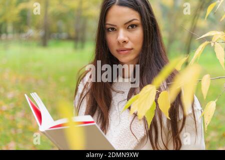 GIOVANE DONNA ASIATICA BELLA CAPELLI MARRONI CAMMINA ATTRAVERSO LA FORESTA IN AUTUNNO Foto Stock