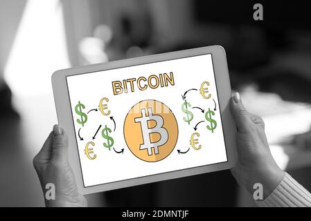 Il concetto di Bitcoin mostrato su un tablet tenuto da una donna Foto Stock