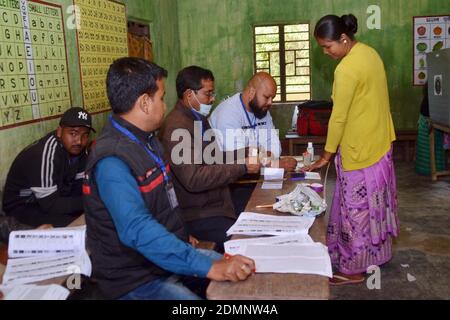 Nagaon, Assam, India - 17 dicembre 2020: Un funzionario elettorale impegnato a dare il segno sul dito di un elettore in una stazione di polling durante le elezioni del Consiglio autonomo di Tiwa nel villaggio di Kachamari nel distretto di Nagaon ad Assam, India. Credit: Dita TALUKDAR/Alamy Live News Foto Stock