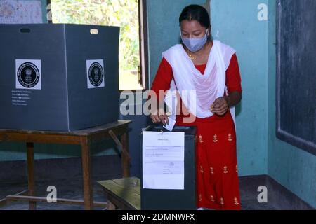 Nagaon, Assam, India - 17 dicembre 2020: Una votante femminile in maschera a causa di Covid - 19 pandemia deposita il giornale di voto nella casella di voto ad una stazione di polling durante l'elezione del Consiglio autonomo di Tiwa nel villaggio di Kachamari nel distretto di Nagaon di Assam, India il giovedì. Credit: Dita TALUKDAR/Alamy Live News Foto Stock