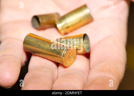 primo piano di custodie in bronzo su una mano in un poligono di tiro o in una scena criminale. concetto di crimine Foto Stock