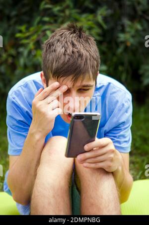 Sorpresa giovane uomo con un cellulare in estate Parcheggio Foto Stock