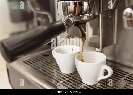 Primo piano di una macchina da caffè con due tazze. Caffè preparato presso il locale caffè attrezzatura bevande bevanda bevanda birra calda mattina prima colazione espresso ca Foto Stock