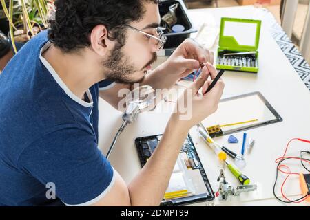 Un riparatore di computer che ripara i componenti del dispositivo elettronico Foto Stock