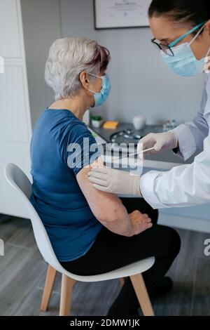 Donna anziana vaccinata contro il coronavirus da un medico femminile Foto Stock