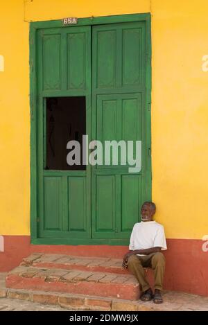 Vecchio seduto di fronte a una casa coloniale, Trinidad Cuba Foto Stock