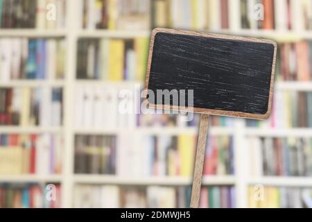 Etichetta lavagna vuota e libreria sfocata sullo sfondo. Risorse grafiche Foto Stock