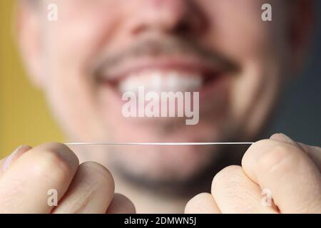 Uomo sorridente che tiene il filo interdentale nelle mani Foto Stock