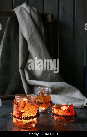 Lanterna autunnale in vaso di vetro decorata con foglie colorate e corona di erica. Candela all'interno. Foto Stock