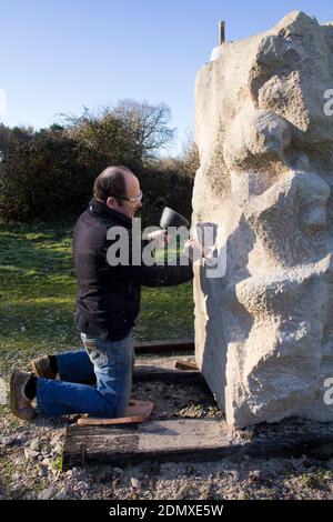 Scultura in pietra scultura scultura sculture in pietra su pulborogh ruscelli RSPB riserva naturale 2014. Scheggiando via con uno scalpello e un mazzuolo Foto Stock