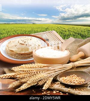 Farina di grano, Chapati, Roti, grappolo di spighe di grano, grani secchi, farina in terracota ciotola su grano di fondo fattoria. Raccolta di cereali, prodotti da forno. Foto Stock