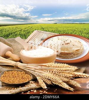 Farina di grano, Chapati, Roti, grappolo di spighe di grano, grani secchi, farina in terracota ciotola su grano di fondo fattoria. Raccolta di cereali, prodotti da forno. Foto Stock