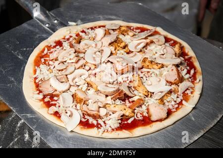 Il processo di fare la pizza. Preparare la pizza su una pala prima di cuocere in forno Foto Stock