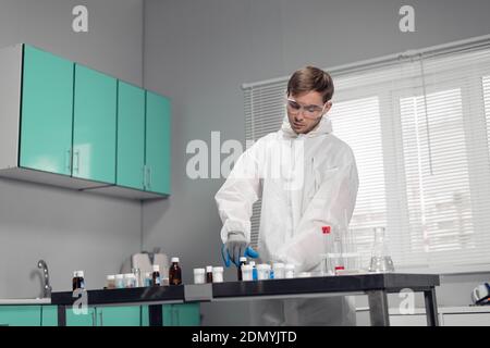 A clinician studying a new substance in a laboratory. Young handsome chemist working in the lab. Stock Photo