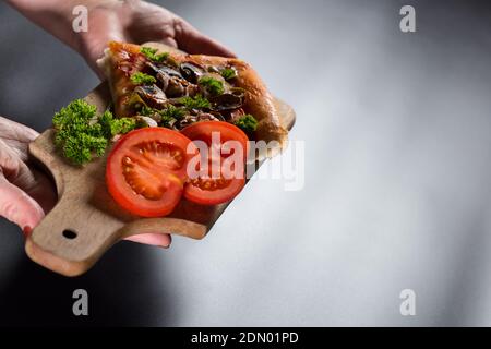 Serve una fetta di pizza su un tavolo da cucina in legno, con spazio per la copia. Foto Stock