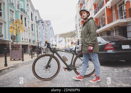 Foto a lunghezza intera di una giovane donna che attraversa la strada con la sua bicicletta Foto Stock