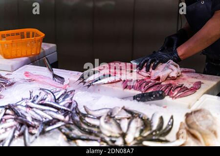 Seller cleans and chops fish at a fish market in Barcelona Foto Stock
